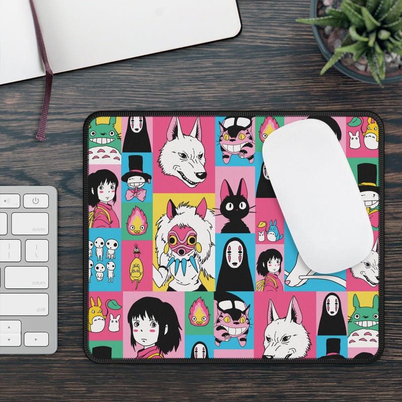 May include: A rectangular mousepad featuring a colorful grid pattern with various anime characters. The design includes characters in pink, yellow, blue, and black squares. A white computer mouse rests on the pad.