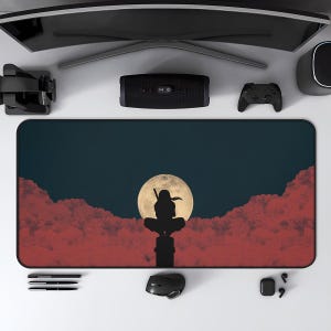 May include: A rectangular mouse pad featuring a silhouette of a figure against a full moon and red clouds. The design is set against a dark blue background. The mouse pad is surrounded by computer accessories.