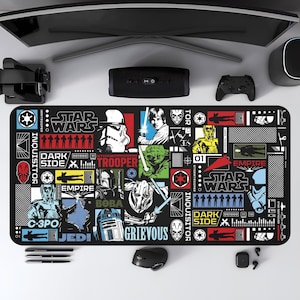 May include: Black rectangular desk mat featuring Star Wars characters and logos. The mat includes images of Darth Vader, Yoda, and Stormtroopers, with the words "Star Wars," "Dark Side," and "Empire."