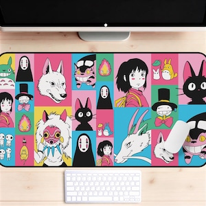 May include: A rectangular mousepad featuring a colorful grid of anime characters. The design includes characters like No-Face, Totoro, and others in a variety of colors. A white keyboard and mouse are in the foreground.