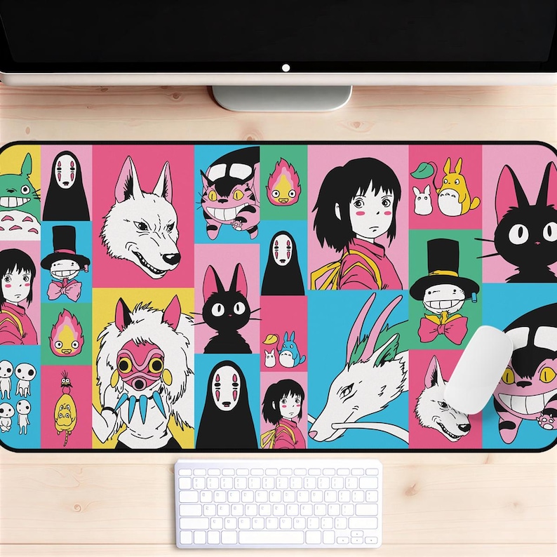 May include: A rectangular mousepad featuring a colorful grid of anime characters. The design includes characters like No-Face, Totoro, and others in a variety of colors. A white keyboard and mouse are in the foreground.