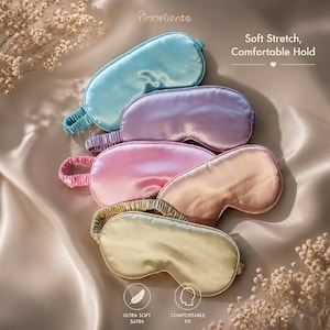 May include: An assortment of satin sleep masks in shades of blue, purple, pink, peach, and gold. The masks are arranged on a silky, neutral-toned surface. Text on the image reads "Soft Stretch, Comfortable Hold" and "Ultra Soft Satin, Comfortable Fit."