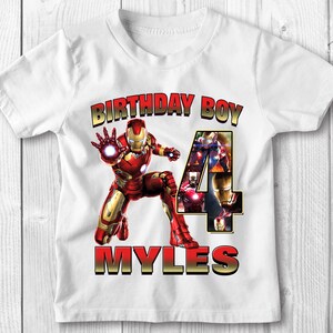 Może przedstawiać: Biała koszulka z grafiką czerwonego i złotego Iron Mana, liczbą 4 złożoną z obraz&oacute;w Iron Mana, tekstem "Birthday Boy" i imieniem "Myles".