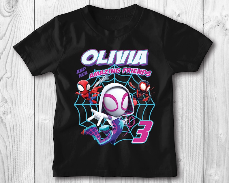 May include: Black t-shirt featuring a graphic of Spider-Gwen and two other Spider-Man characters. The text "Olivia and her Amazing Friends" is printed on the shirt. The number "3" is also printed on the shirt.