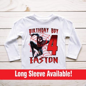 Op de afbeelding: Een wit shirt met lange mouwen met een rode en zwarte Spider-Man afbeelding, de tekst "Birthday Boy" en het nummer "4" in rood. De naam "Easton" staat in rood onder het nummer. De tekst "Long Sleeve Available!" staat in rood onderaan de afbeelding.