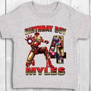 Może przedstawiać: Szara koszulka z grafiką Iron Mana w kolorze czerwonym i złotym, tekstem "Birthday Boy" i cyfrą "4" złożoną z obraz&oacute;w Iron Mana. Imię "Myles" jest napisane złotem pod grafiką.