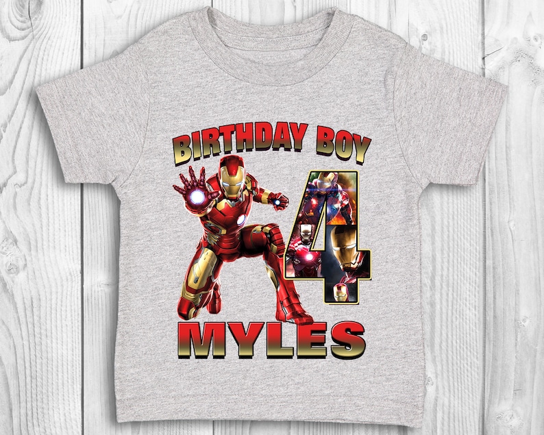 Może przedstawiać: Szara koszulka z grafiką Iron Mana w kolorze czerwonym i złotym, tekstem "Birthday Boy" i cyfrą "4" złożoną z obraz&oacute;w Iron Mana. Imię "Myles" jest napisane złotem pod grafiką.