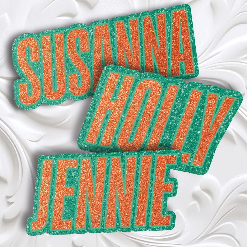 May include: Three glittery name cutouts: "SUSANNA", "HOLLY", and "JENNIE". Each name is in orange glitter with a green glitter outline. The names are arranged at different angles against a white, textured background.