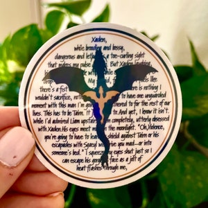 May include: A white round sticker with a black silhouette of a dragon and gold accents. The sticker features a quote about a character named Xaden, who is brooding and bossy, and a character named Taim, who is dangerous and lethal. The quote reads: "Xaden, while brooding and bossy, dangerous and lethal... there's a fist I wouldn't sacrifice, nothing I'd do to have one unguarded moment with this man. I'm going to have to for the rest of our lives. This has to be Taim. It's completely, utterly obsessed with Xaden. His eyes meet mine in the moonlight. "Oh, Violence, you're going to have to learn to shield against Taim or his escapades with Sgaeul, who might drive you mad - or into someone's bed." I squeeze my eyes shut just so I can escape his gorge face as a jolt of heat flashes through me."