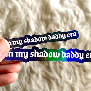 May include: Two iridescent holographic stickers with the text "in my shadow daddy era" in white gothic font.