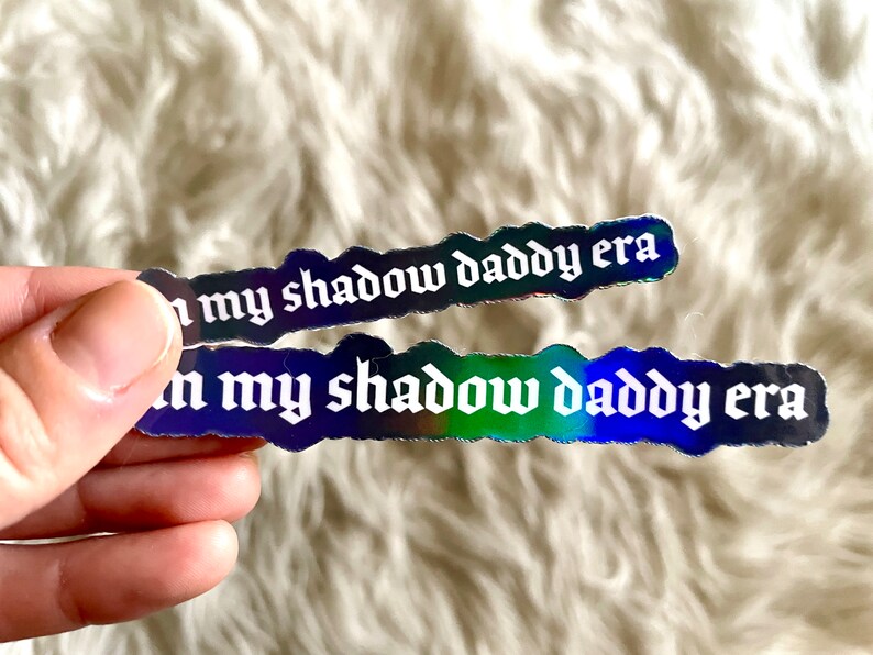 May include: Two iridescent holographic stickers with the text "in my shadow daddy era" in white gothic font.