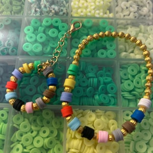 May include: A colorful bracelet made with small round beads and gold spacers. The bracelet is displayed on a white background with a variety of small round beads in different colors.