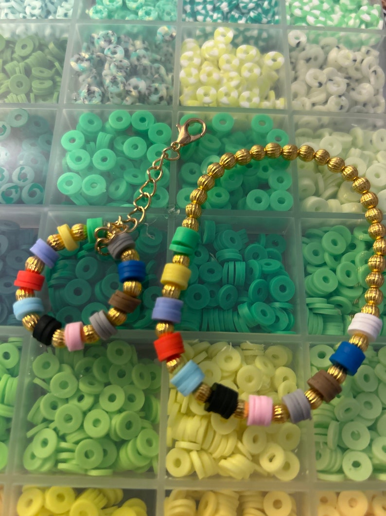 May include: A colorful bracelet made with small round beads and gold spacers. The bracelet is displayed on a white background with a variety of small round beads in different colors.