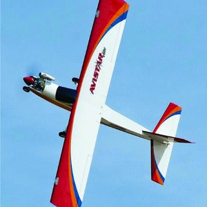 Puede incluir: Un avión radiocontrolado rojo, blanco y azul con el texto "Avistar Elite" en el lateral. El avión está en vuelo contra un cielo azul.