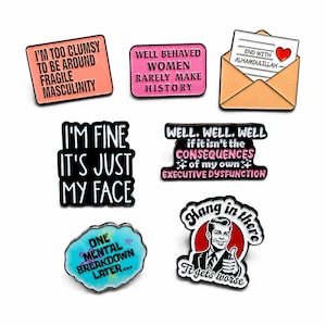 May include: A collection of six enamel pins featuring various phrases: I'M TOO CLUMSY TO BE AROUND FRAGILE MASCULINITY, WELL BEHAVED WOMEN RARELY MAKE HISTORY, END WITH ALHAMDULILLAH, I'M FINE IT'S JUST MY FACE, CONSEQUENCES OF MY OWN EXECUTIVE DYSFUNCTION, ONE MENTAL BREAKDOWN LATER, and a retro illustration with the text Hang in there It gets worse.