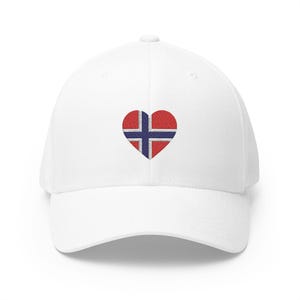 Könnte beinhalten: Weiße Baseballkappe mit einem herzförmigen Design der norwegischen Flagge in Rot, Weiß und Blau. Die Kappe hat einen gebogenen Schirm und eine strukturierte Passform.