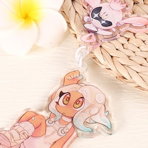 May include: A white and pink anime character keychain with a white and blue anime character keychain attached. The keychain features a white background with pink and blue accents.