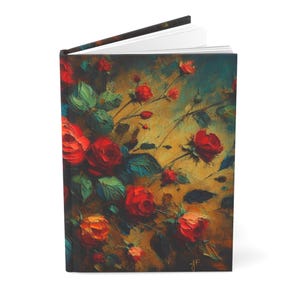 May include: A hardcover journal featuring an oil painting style print of vibrant red roses and green leaves against a dark, textured golden-brown background. The book is slightly open, revealing white pages along the top edge of the binding.