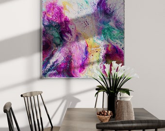 May include: A dining room table with four black chairs, a vase of white calla lilies, and a bowl of nuts. A colorful abstract painting hangs on the wall behind the table.