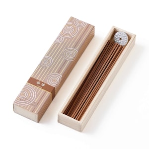 May include: A set of thin brown incense sticks inside a rectangular wooden box, accompanied by a matching lid featuring a brown and white circular pattern and the text 珈琲 Coffee Kousaido Kyoto Japan, plus a small circular metal incense holder.
