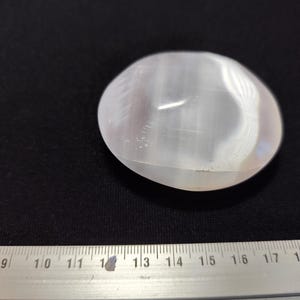 Peut inclure: Une pierre de paume en sélénite blanche avec une surface lisse et polie. La pierre mesure environ 3,8 cm de diamètre.