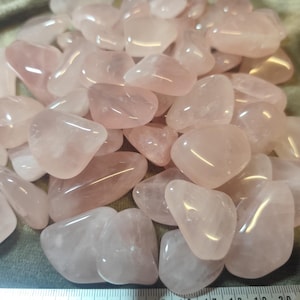 Peut inclure: Un tas de pierres de quartz rose polies. Les pierres sont d'une couleur rose tendre, avec des formes lisses et arrondies. La lumière se reflète sur la surface des pierres, créant des reflets. Ces pierres sont populaires pour les bijoux et la décoration.