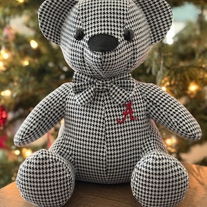 May include: A black and white houndstooth teddy bear wearing a black bow tie and a red embroidered letter "A".