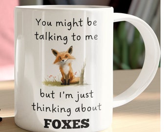 May include: White ceramic mug featuring a fox illustration and the text "You might be talking to me but I'm just thinking about FOXES".
