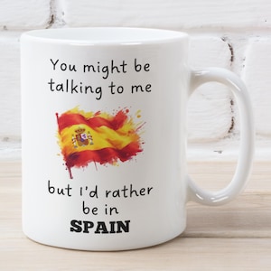 May include: White ceramic mug with a black and white graphic that says "You might be talking to me but I'd rather be in SPAIN". The graphic also includes a watercolour-style Spanish flag.