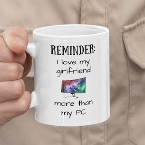 Pode incluir: Caneca de cerâmica branca com um gráfico preto e branco que diz "LEMBRETE: Amo minha namorada mais do que meu PC". O gráfico também inclui uma imagem estilizada de um monitor de computador.