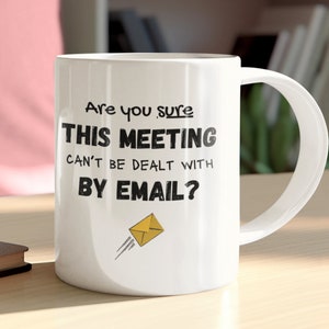 May include: White ceramic coffee mug with black text that reads "Are you sure THIS MEETING can't be dealt with BY EMAIL?" with a yellow cartoon envelope flying to the right.