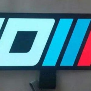 May include: White JDM logo with blue, red, and white stripes. The logo is illuminated with white LED lights.