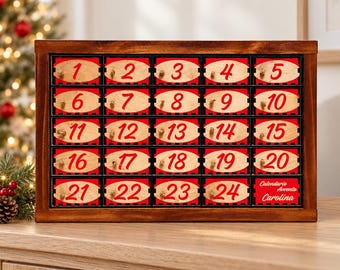 May include: A rectangular wooden advent calendar with twenty-four numbered drawers. Each drawer features a light wood oval label with a red number from 1 to 24. The final drawer displays the text Calendario Avento Carolina in red script.
