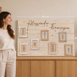May include: A wooden wedding seating chart, 90 cm wide and 60 cm tall, with the names "Alessandro" and "Francesca" in cursive. It features six small framed cards with guest names. The wooden board is light brown.