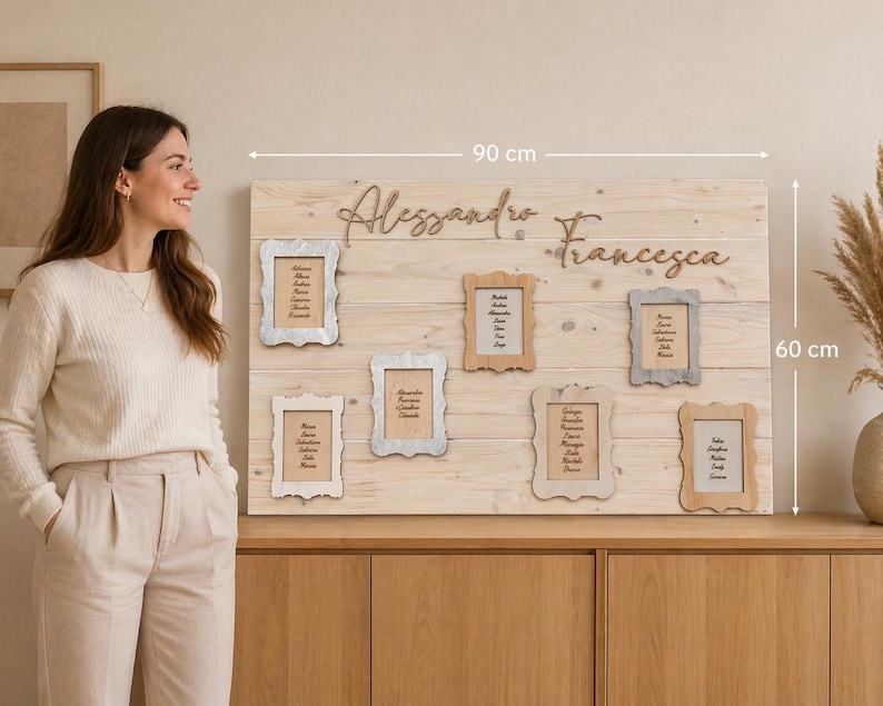 May include: A wooden wedding seating chart, 90 cm wide and 60 cm tall, with the names "Alessandro" and "Francesca" in cursive. It features six small framed cards with guest names. The wooden board is light brown.