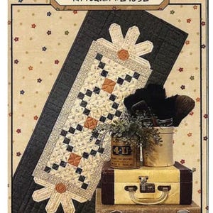 Può includere: Un kit per trapunte intitolato "Daisy Duo" con un design floreale, con un runner da tavolo con estremità a forma di margherita e un motivo a scacchi bianco e nero. L'immagine include una pila di valigie vintage e oggetti decorativi.