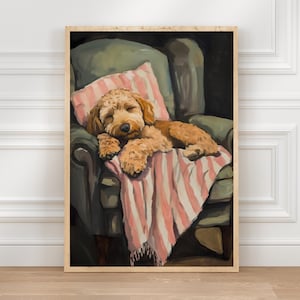 Pode incluir: Impressão emoldurada de um cão a dormir. O cão, com pelo castanho claro, está enrolado numa manta e almofada rosa às riscas, descansando numa poltrona verde. A obra de arte tem um ambiente acolhedor e convidativo, perfeito para decoração de casa.
