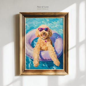 Op de afbeelding: Een ingelijst schilderij van een golden doodle hond met een paarse zonnebril en een roze halsband, drijvend in een zwembad op een paarse en blauwe opblaasbare ring. Het schilderij heeft een gouden lijst en de tekst "Paw of Love" staat bovenaan.