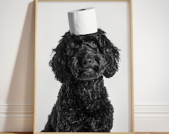 May include: A black and white framed poster titled Paw of Love featuring a black curly-haired dog with a white toilet paper roll balanced on its head. The dog has dark eyes and a textured coat, presented in a light wood frame against a white wall.