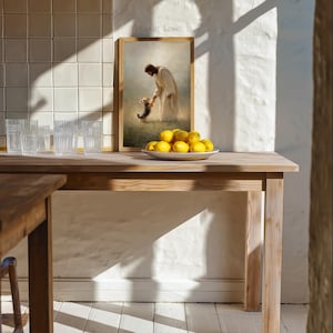 May include: A wooden table with a framed print showing a figure in white robes with a dog. A white plate holds several yellow lemons. Clear drinking glasses are arranged on the table. The text "Paw of Love" is visible.