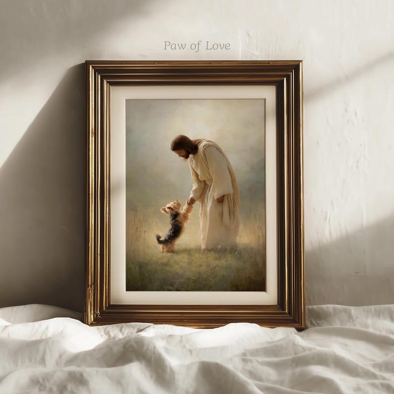 May include: A framed art print depicting a figure in white robes interacting with a small dog in a field. The artwork is set within a gold-coloured frame and includes the text "Paw of Love" at the top.