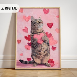 May include: A framed digital print featuring a tabby cat holding a pink heart. The cat is surrounded by various pink and red hearts on a pink background. The print has a wooden frame and the word "DIGITAL" is in the top left corner.