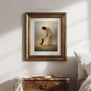 May include: Framed art print depicting a person in a white robe interacting with a small dog in a grassy field. The artwork is in a gold-coloured frame. The text "Paw of Love" is in the upper left corner.