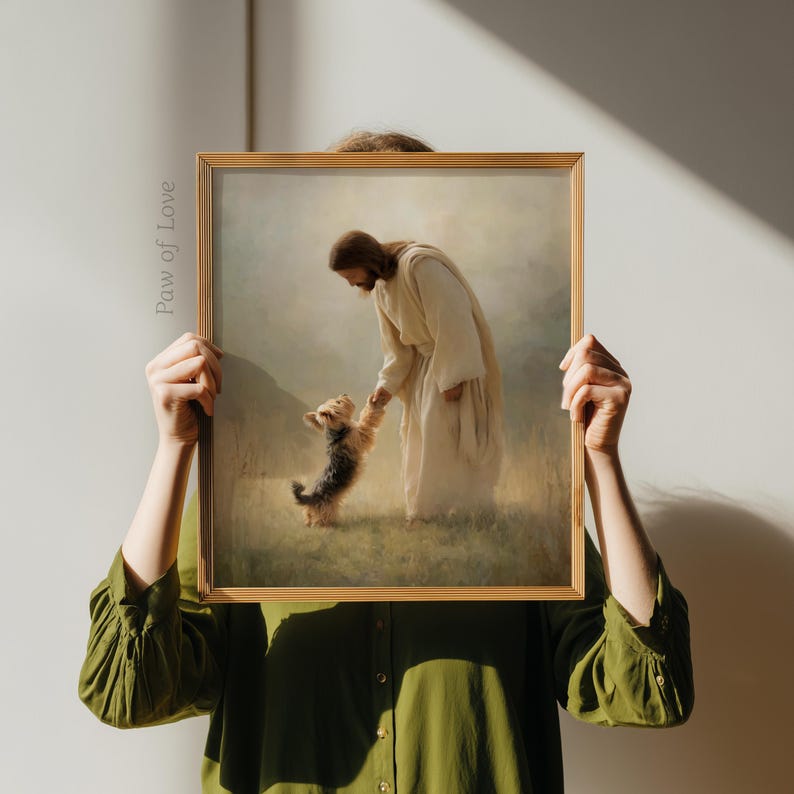 May include: A framed print depicting a religious scene with a figure in white robes interacting with a small dog. The artwork has a soft, painterly style and is set within a golden frame. The text "Paw of Love" is visible on the left side of the frame.