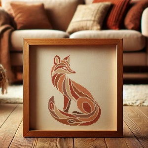 May include: A framed cross-stitch artwork featuring a geometric fox design in shades of brown, orange, and beige. The fox is sitting with its tail curled around its body.