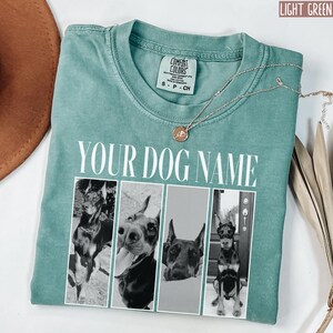 May include: Light green t-shirt with a white text overlay that says "YOUR DOG NAME". The shirt features four black and white photos of dogs in a collage.