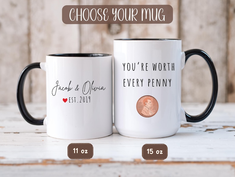 May include: Two white ceramic mugs with black handles and rims. One mug has "Jacob & Olivia EST. 2019" printed on it. The other mug says "YOU'RE WORTH EVERY PENNY" with a penny graphic. The mugs are 11 oz and 15 oz.