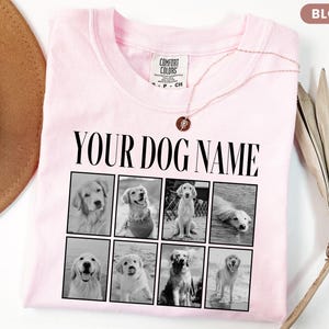 May include: A light pink t-shirt featuring the black text "YOUR DOG NAME" above a grid of eight black and white photographs of golden retriever dogs. The shirt has a crew neckline and a Comfort Colors brand label on the inside collar.