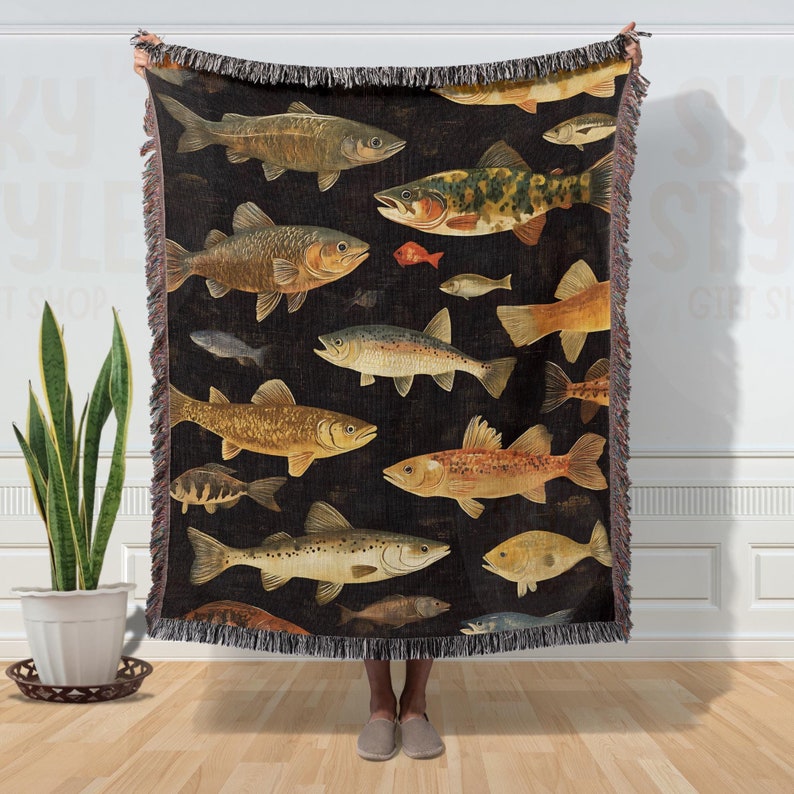 May include: A woven throw blanket with a dark background and a pattern of colorful fish. The fish are arranged in a random pattern and are of different sizes and shapes.