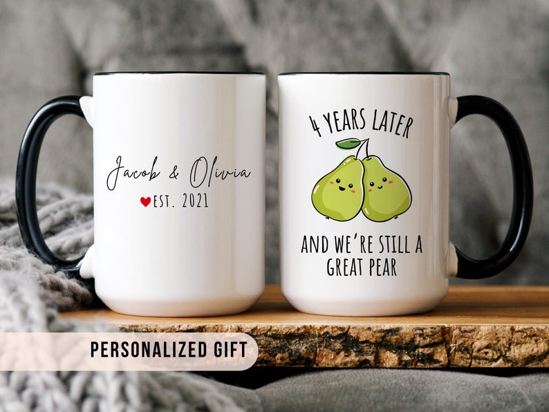 White ceramic mug set with black handles, featuring custom names and "Est. 2021" on one side, and two cute pears illustration with the phrase "4 years later and we’re still a great pear" on the other.